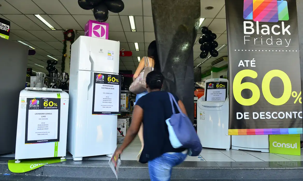 Calendário de promoções 2026: todas as datas para economizar (e quando comprar cada coisa) 6 Pessoas entrando em loja de eletrodomésticos com banner de Black Friday anunciando até 60% off