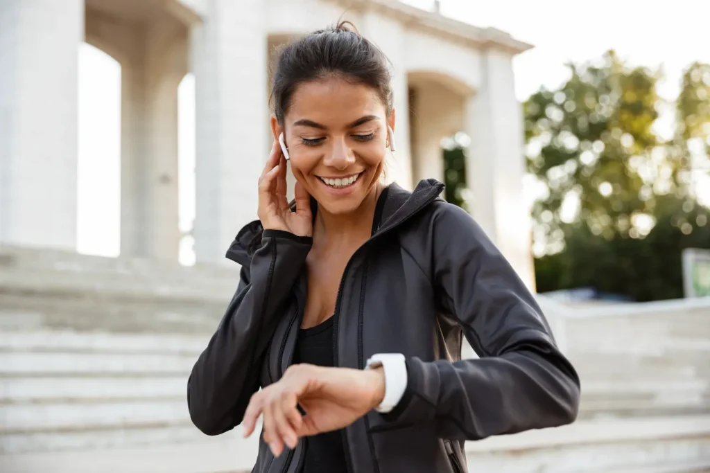 Smartwatch barato vale a pena? O que esperar dos modelos de entrada antes de gastar em 2026 2 Mulher verificando métricas em smartwatch durante corrida ao ar livre, destacando praticidade no uso cotidiano.