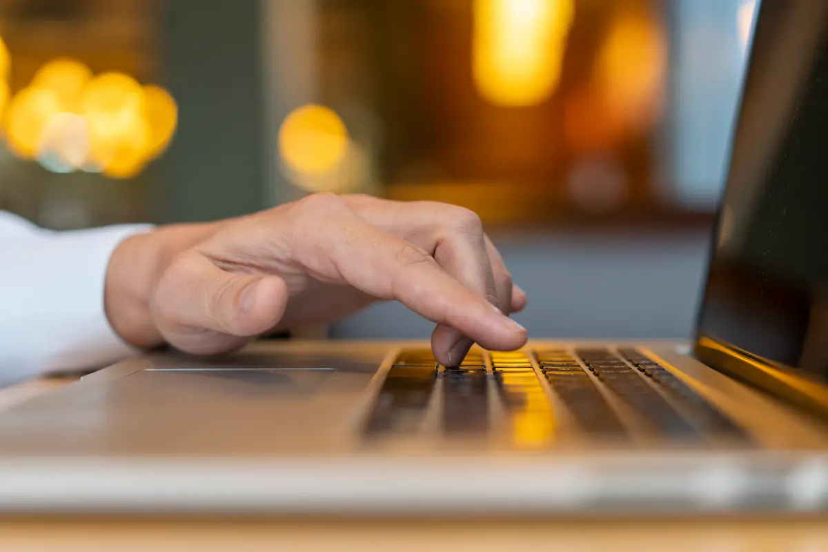 Imóveis com até 50% de desconto: Caixa anuncia novo leilão com mais de 80 oportunidades 2 Mão de pessoa usando notebook para acessar leilão de imóveis pela internet.